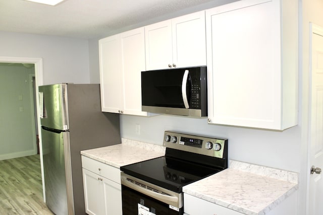 kitchen featuring stainless steel appliances, white cabinetry, and light wood-type flooring