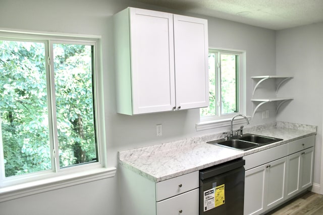 kitchen featuring light wood-type flooring, sink, black dishwasher, and white cabinets