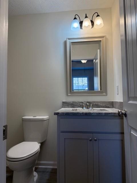 bathroom featuring vanity, toilet, hardwood / wood-style floors, and a textured ceiling