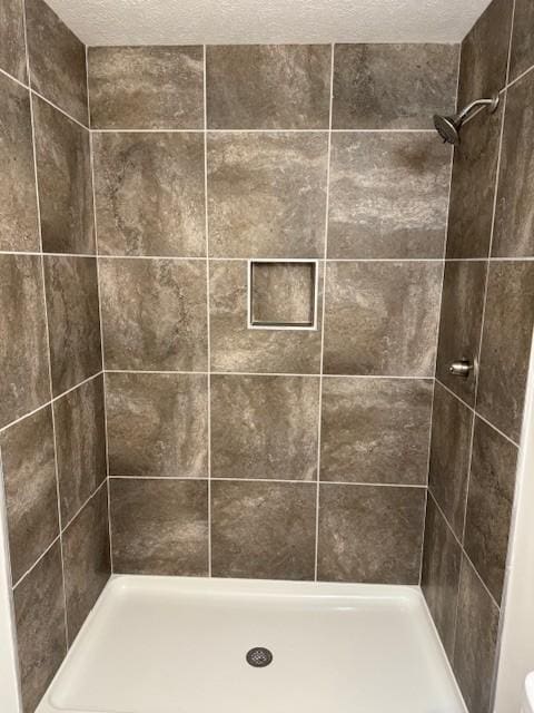 bathroom with a tile shower and a textured ceiling