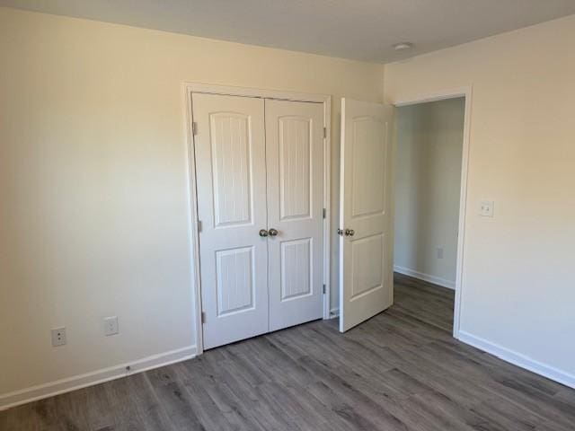 unfurnished bedroom with dark wood-type flooring and a closet