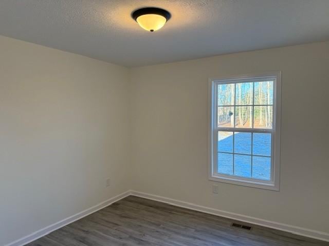 unfurnished room with dark hardwood / wood-style floors and a textured ceiling