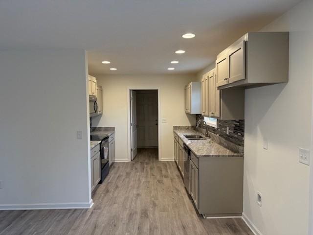 kitchen with sink, appliances with stainless steel finishes, light stone counters, decorative backsplash, and light wood-type flooring