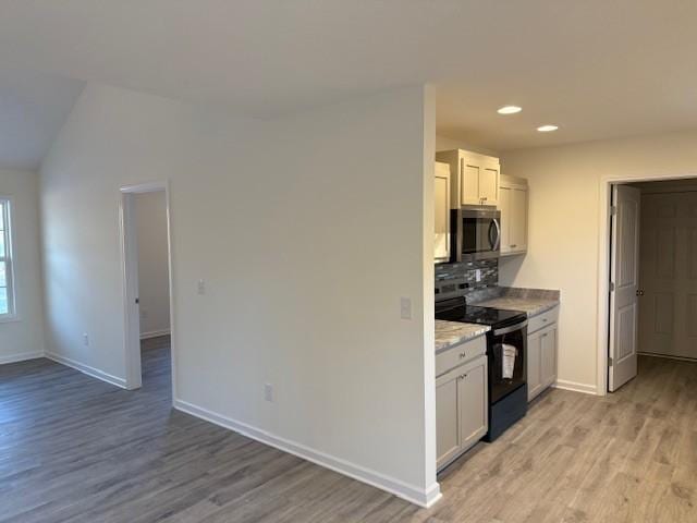 kitchen with white cabinetry, decorative backsplash, black electric range, and light hardwood / wood-style flooring