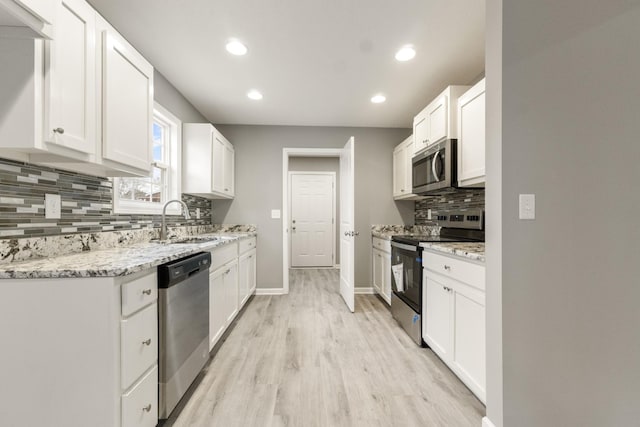 kitchen with sink, stainless steel appliances, white cabinetry, and light stone countertops