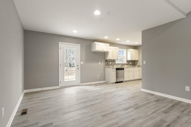 kitchen featuring white cabinets, stainless steel dishwasher, light hardwood / wood-style flooring, and decorative backsplash