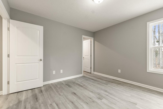 unfurnished room with light wood-type flooring and a textured ceiling