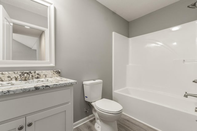 full bathroom featuring wood-type flooring, washtub / shower combination, vanity, and toilet