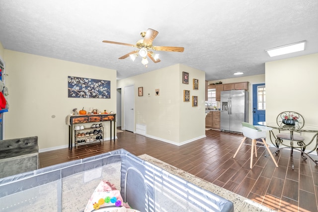 living room featuring dark wood-type flooring, ceiling fan, and a textured ceiling