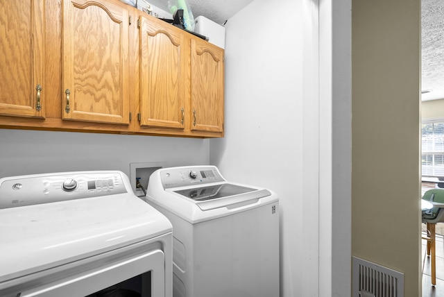 laundry room featuring cabinets, independent washer and dryer, and a textured ceiling