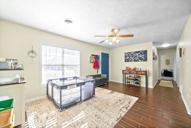 living room featuring ceiling fan, a textured ceiling, and dark hardwood / wood-style floors