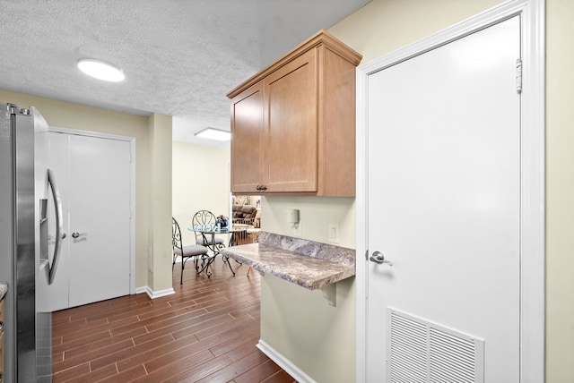 kitchen featuring stainless steel fridge, a textured ceiling, and dark hardwood / wood-style flooring