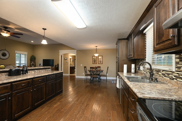 kitchen featuring sink, dark brown cabinets, dark hardwood / wood-style flooring, pendant lighting, and extractor fan