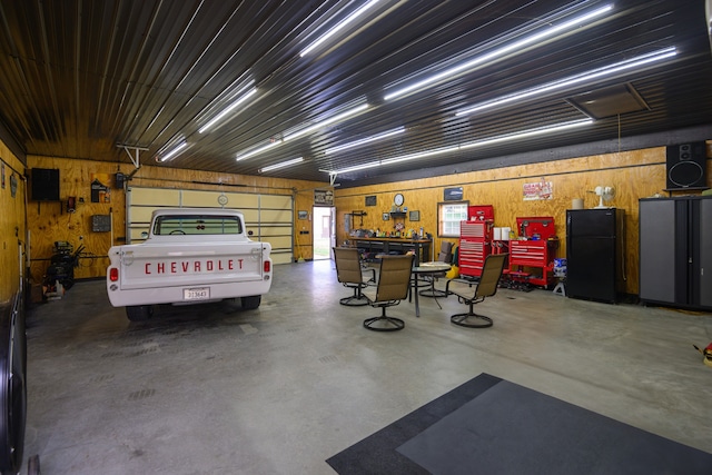 garage with wood walls and black refrigerator