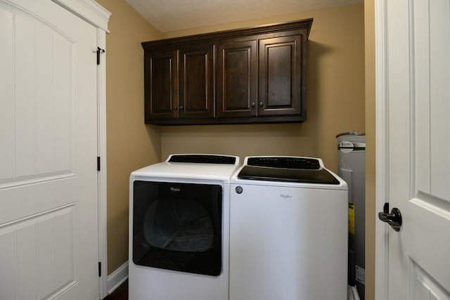 clothes washing area with a textured ceiling, cabinets, and washing machine and clothes dryer