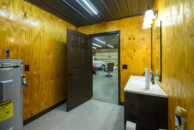 bathroom with water heater, wooden walls, and sink