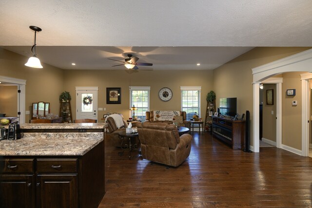 living room with ceiling fan, a textured ceiling, and dark hardwood / wood-style flooring