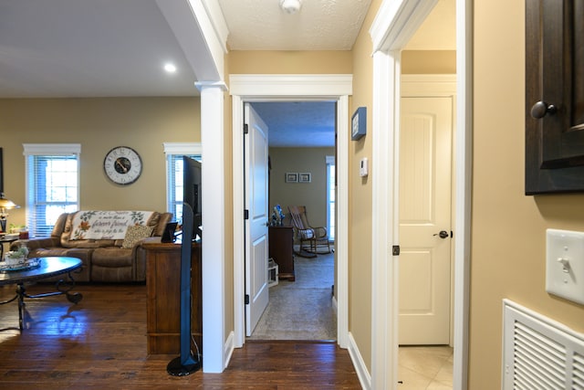 hallway featuring dark wood-type flooring and ornate columns