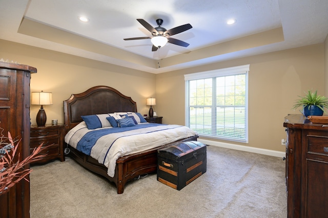 bedroom featuring ceiling fan, a raised ceiling, and light carpet