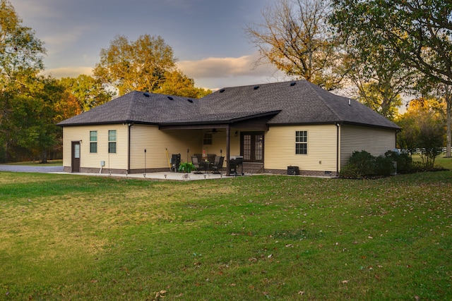 back house at dusk with a yard and a patio area