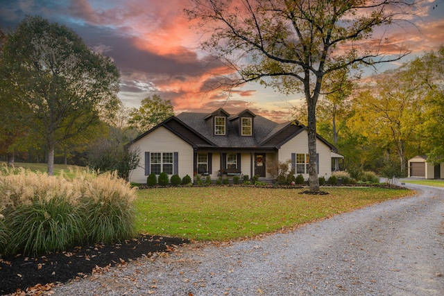 cape cod home with an outdoor structure, a lawn, and a garage