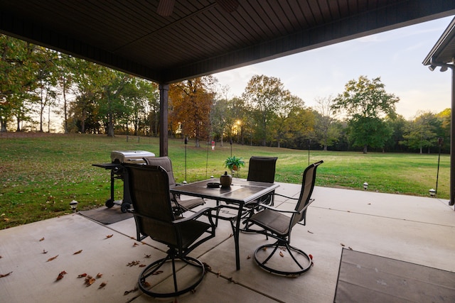 patio terrace at dusk featuring grilling area and a lawn