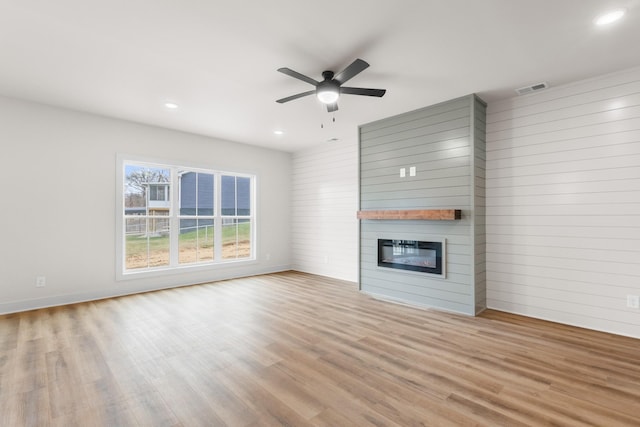 unfurnished living room with a fireplace, light hardwood / wood-style flooring, and ceiling fan