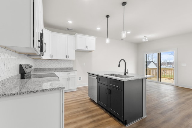 kitchen featuring a kitchen island with sink, white cabinets, sink, decorative light fixtures, and stainless steel appliances