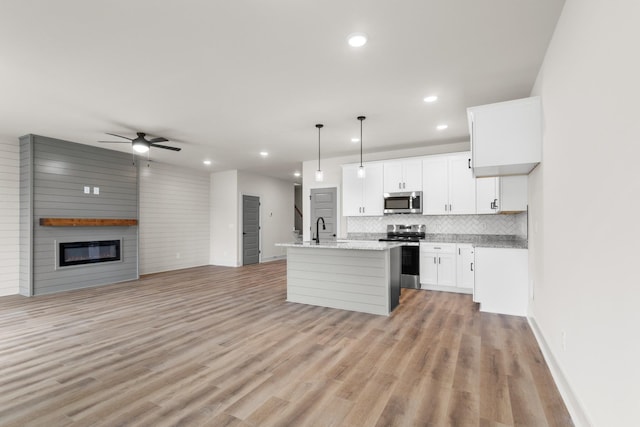 kitchen featuring a kitchen island with sink, light hardwood / wood-style flooring, decorative light fixtures, white cabinetry, and stainless steel appliances