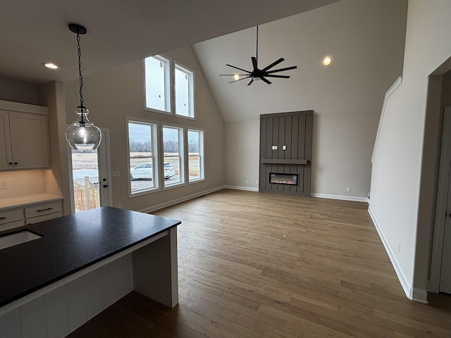 unfurnished living room with hardwood / wood-style floors, high vaulted ceiling, and ceiling fan