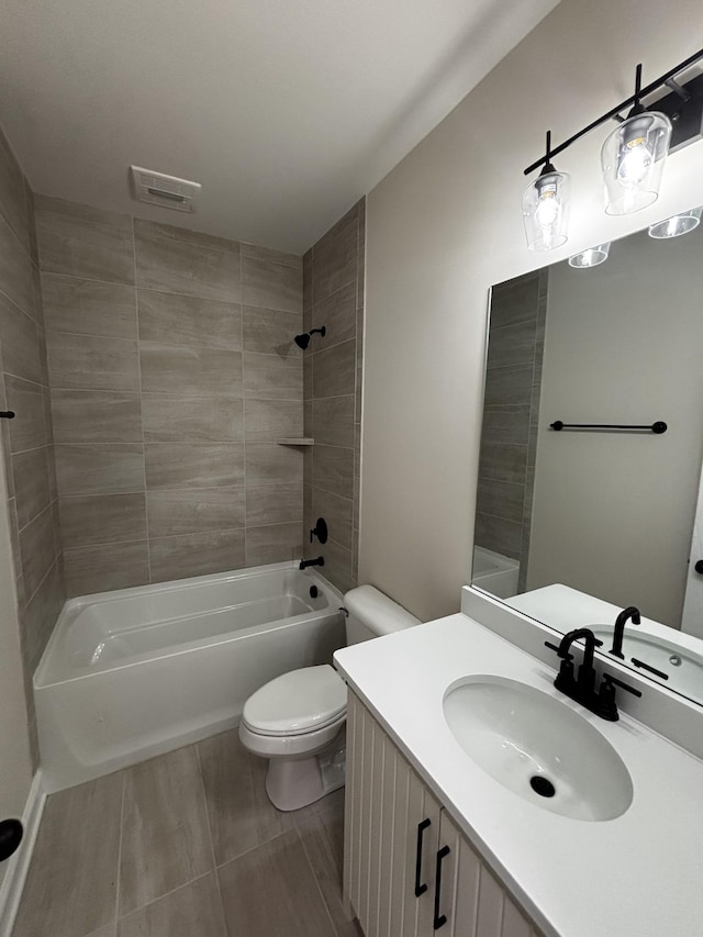 full bathroom featuring tiled shower / bath, vanity, and toilet