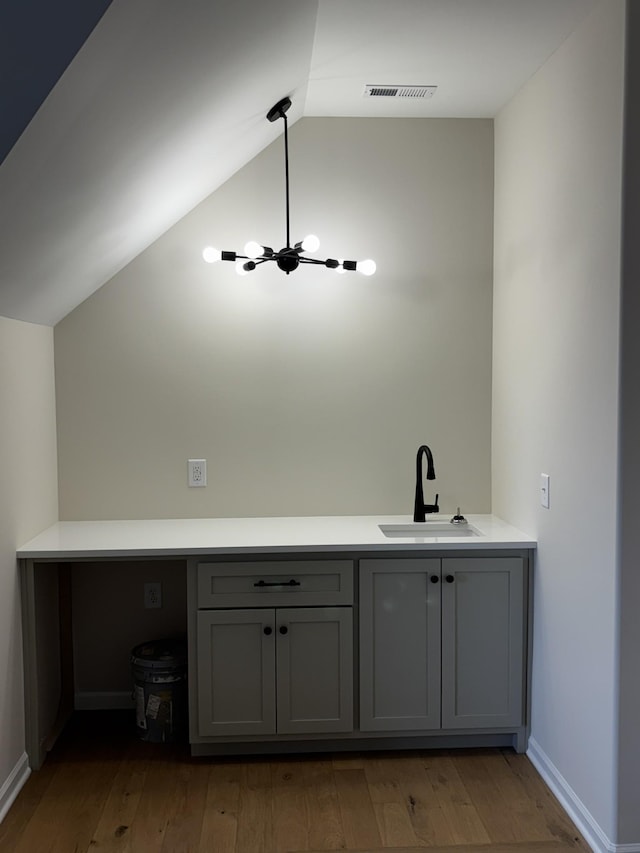 bathroom featuring wood-type flooring, vaulted ceiling, and sink