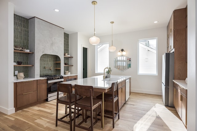 kitchen featuring a kitchen island with sink, plenty of natural light, sink, and light wood-type flooring