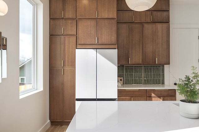 kitchen featuring wood-type flooring, backsplash, and white fridge