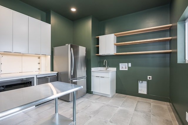 kitchen featuring stainless steel refrigerator, sink, and white cabinets