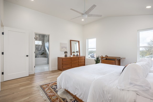 bedroom featuring light wood-type flooring, ensuite bathroom, vaulted ceiling, and ceiling fan