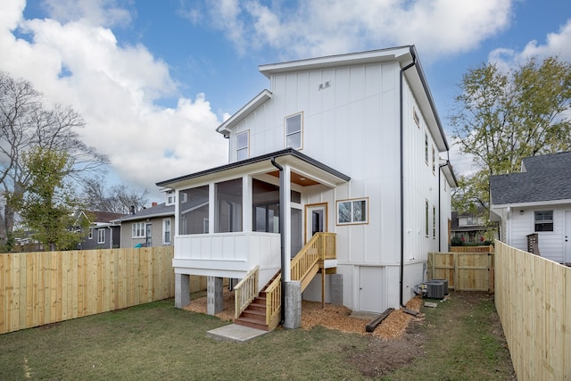 rear view of property with a yard, central air condition unit, and a sunroom