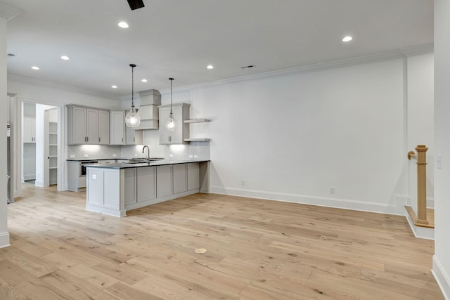 kitchen featuring sink, hanging light fixtures, light wood-type flooring, ornamental molding, and kitchen peninsula