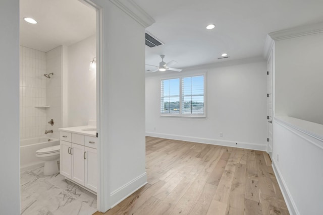 full bathroom with tiled shower / bath, vanity, ceiling fan, toilet, and crown molding