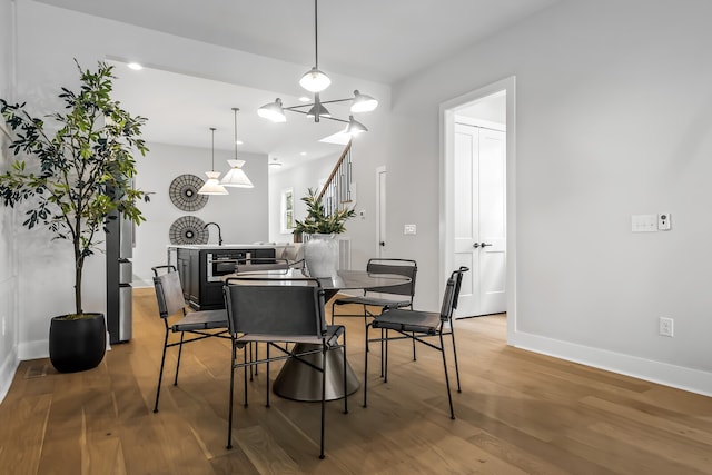 dining area featuring an inviting chandelier, sink, and wood-type flooring