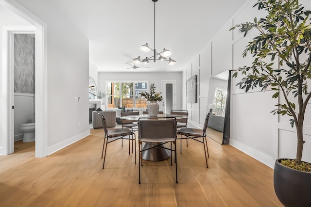 dining room featuring light hardwood / wood-style floors and ceiling fan with notable chandelier