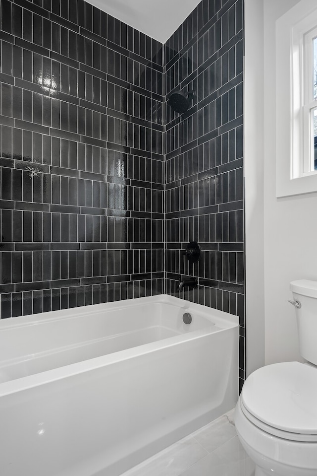 bathroom with toilet and tiled shower / bath