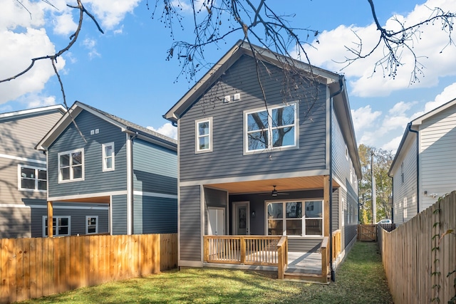 back of property with a yard and ceiling fan