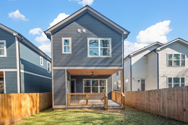 rear view of property featuring a lawn and ceiling fan