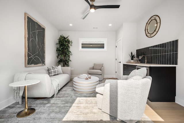 living room with sink, light wood-type flooring, and ceiling fan