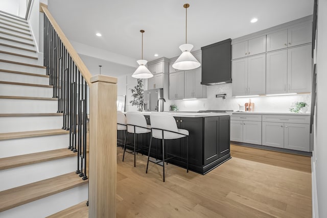 kitchen with light hardwood / wood-style flooring, premium range hood, pendant lighting, and gray cabinetry