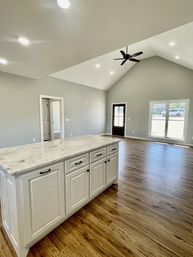 kitchen featuring vaulted ceiling, white cabinetry, wood-type flooring, and a healthy amount of sunlight