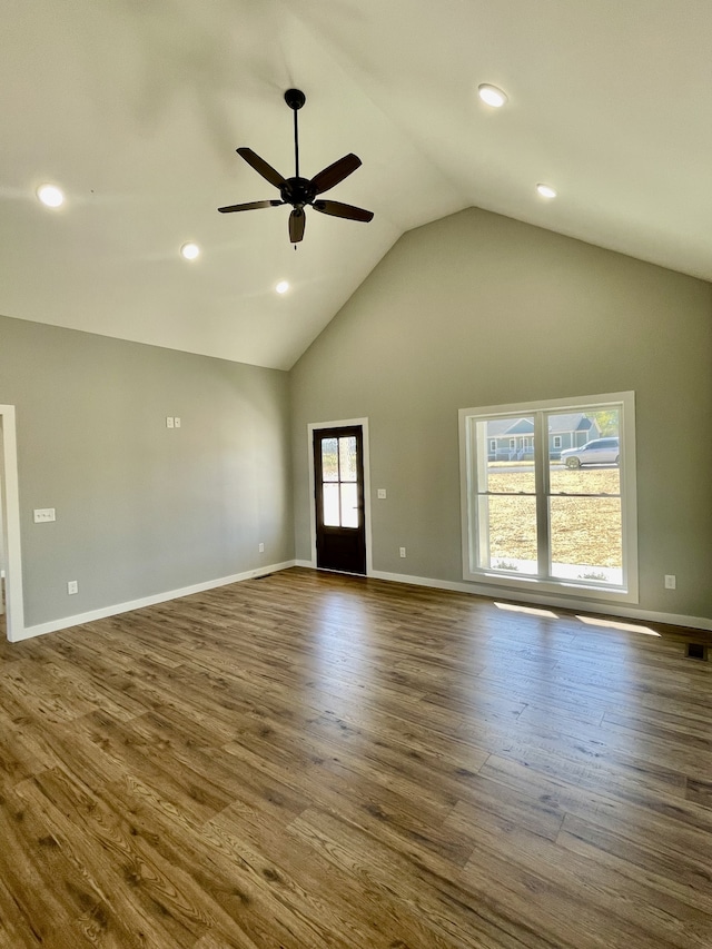 unfurnished living room with ceiling fan, high vaulted ceiling, dark wood-type flooring, and a wealth of natural light