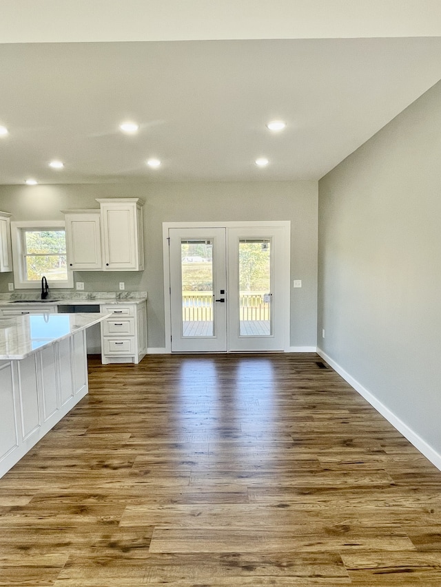 kitchen with a wealth of natural light, sink, white cabinetry, and light hardwood / wood-style floors