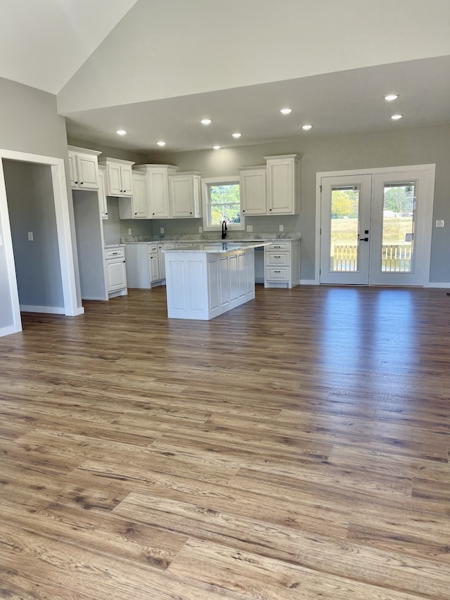 kitchen featuring lofted ceiling, white cabinets, light hardwood / wood-style flooring, sink, and a center island